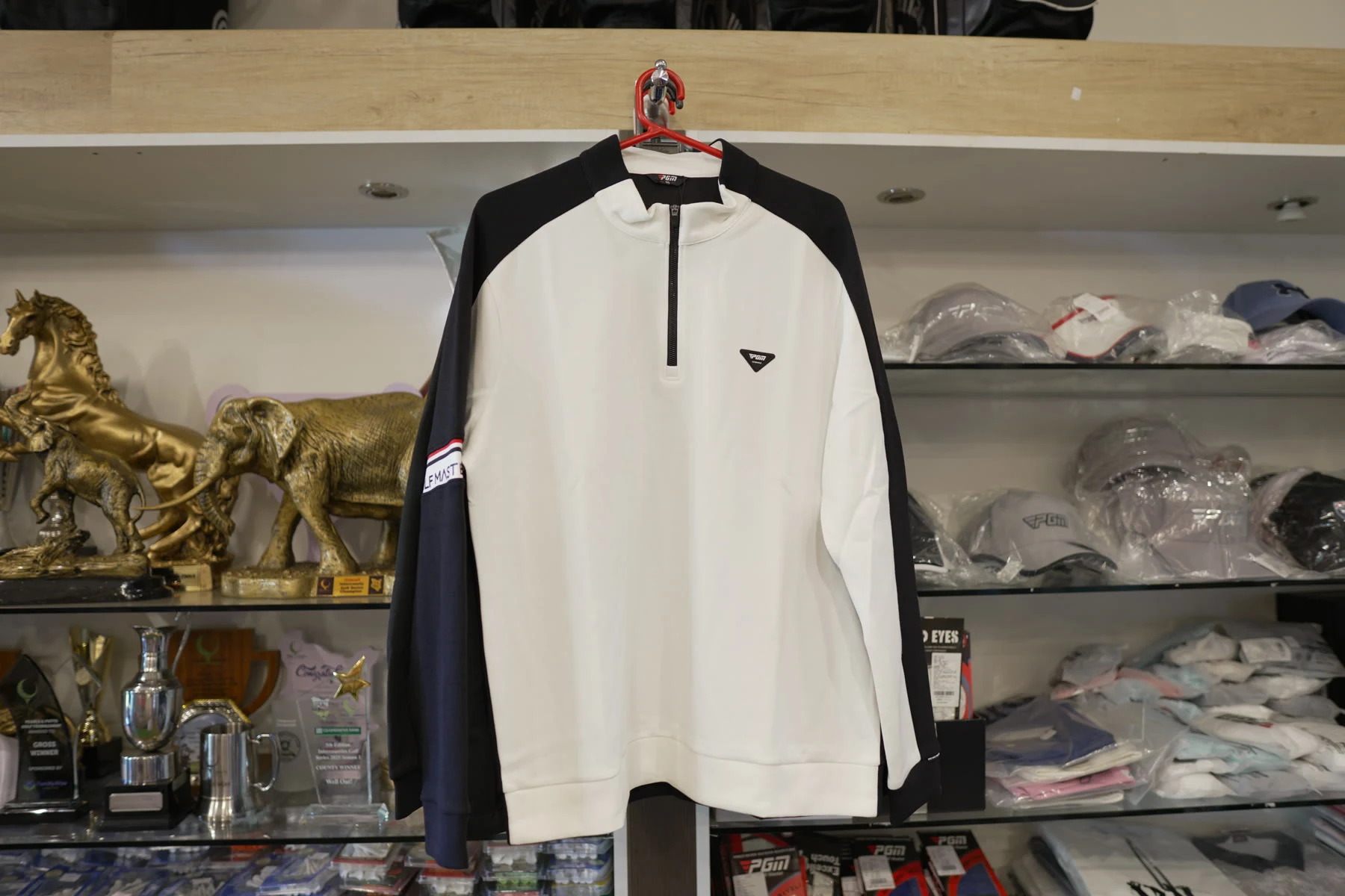 A white and black Callaway quarter-zip midlayer on a hanger in the shop