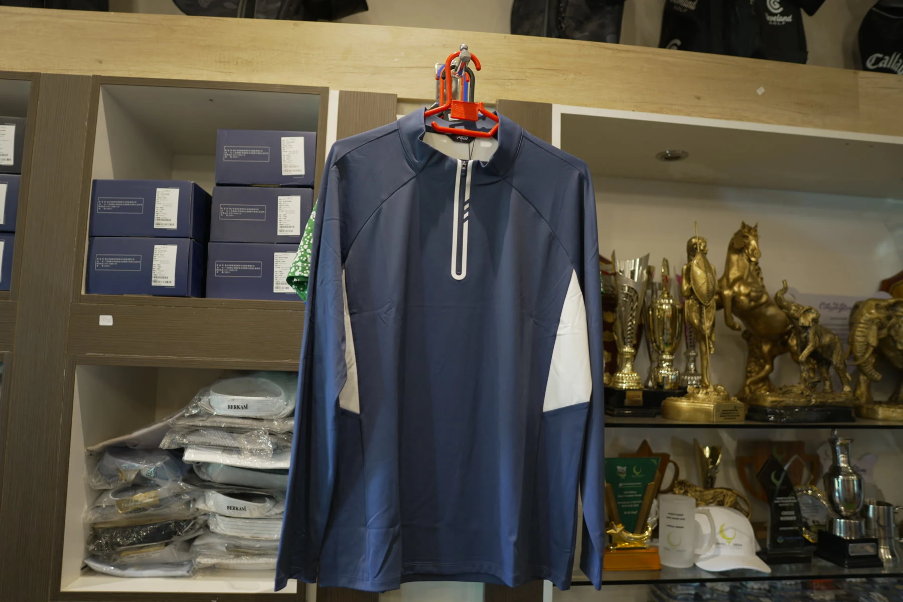 A navy and white PGM half-zip pullover displayed on a hanger