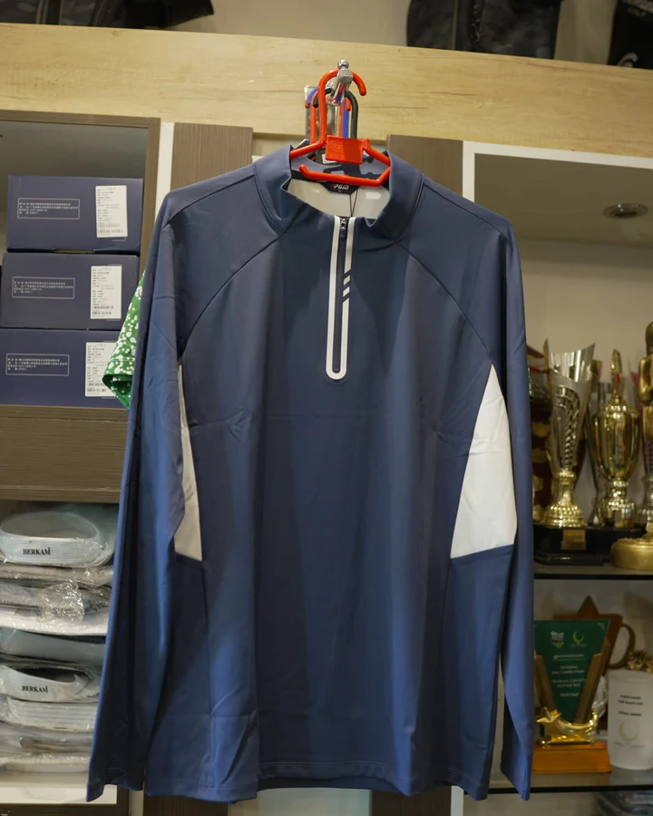 A navy and white PGM half-zip pullover displayed on a hanger