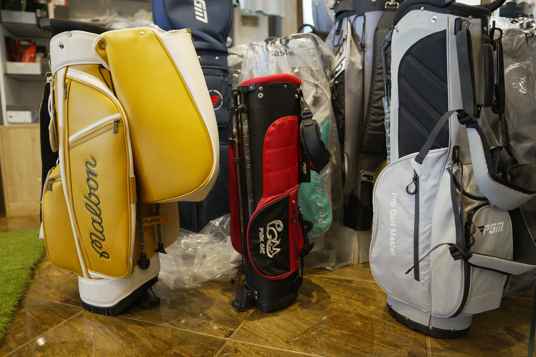 A yellow Malbon cart bag standing among other golf bags in the shop