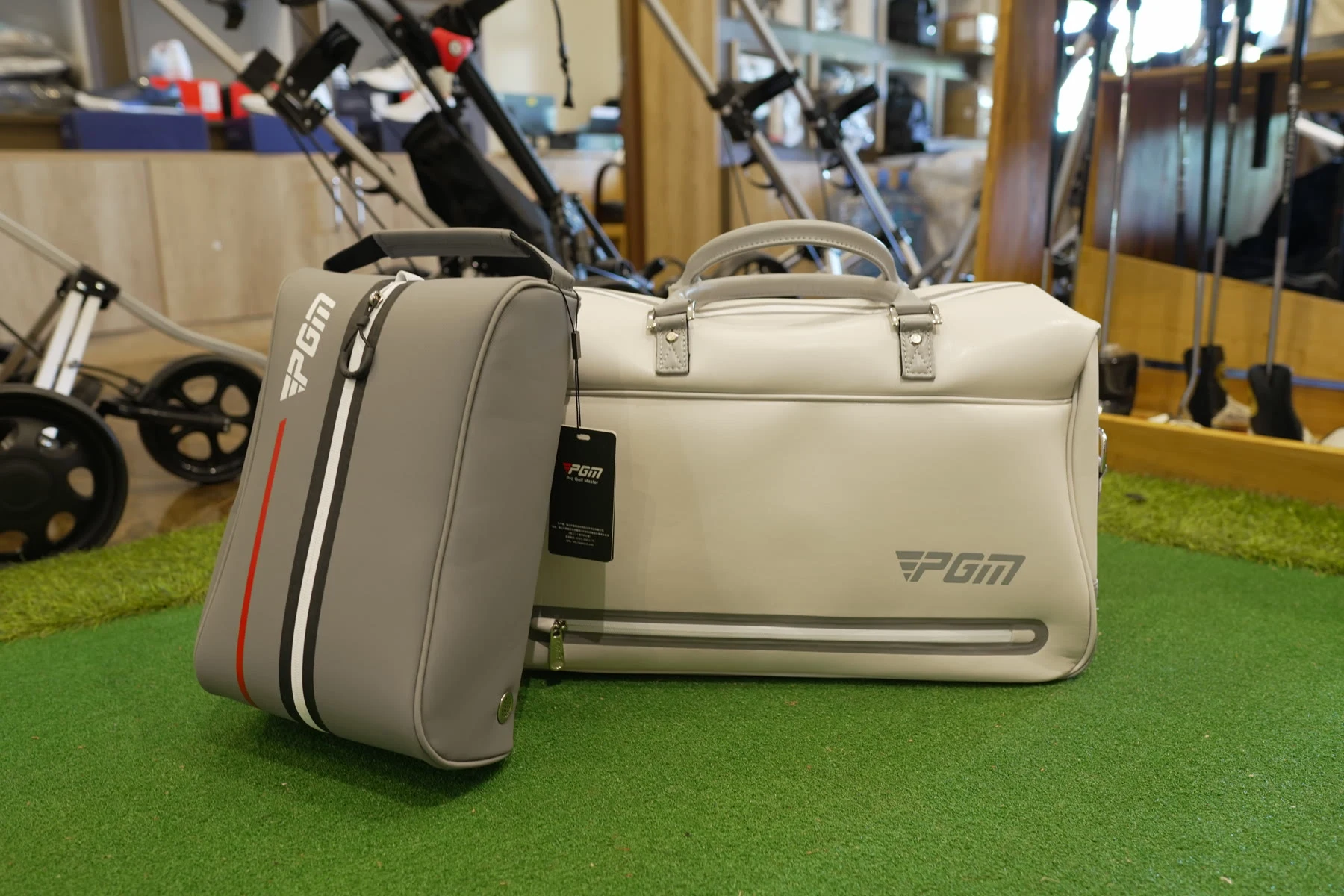 A cream PGM travel duffel bag standing on the shop's putting turf