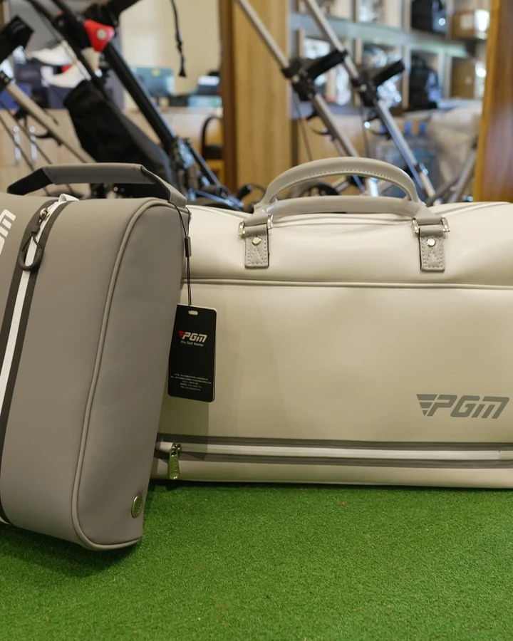 A cream PGM travel duffel bag standing on the shop's putting turf