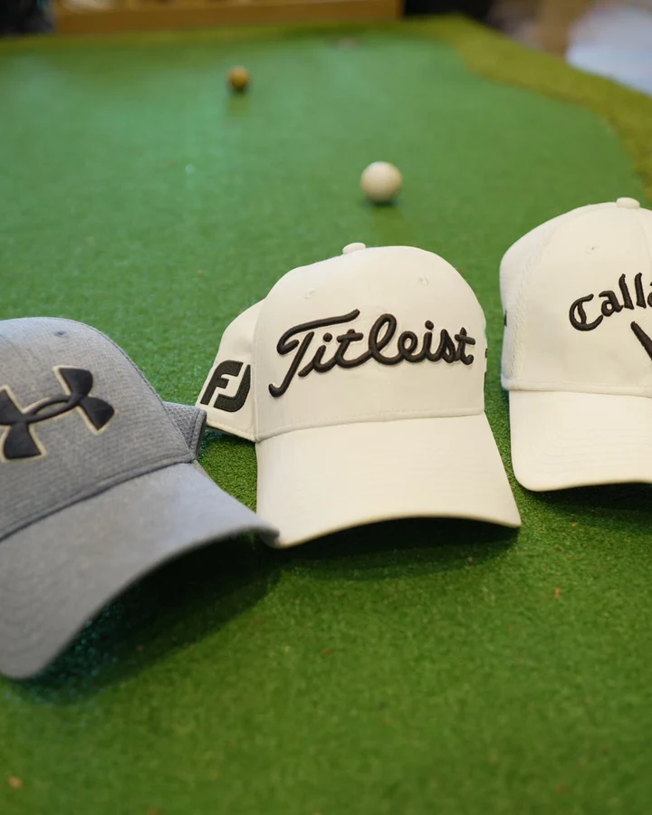 Under Armour, Titleist and Callaway caps arranged on the shop's putting turf