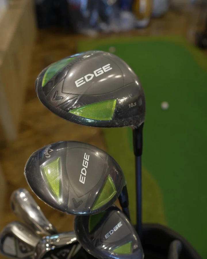 A Callaway Edge driver head resting in a golf bag beside the putting green
