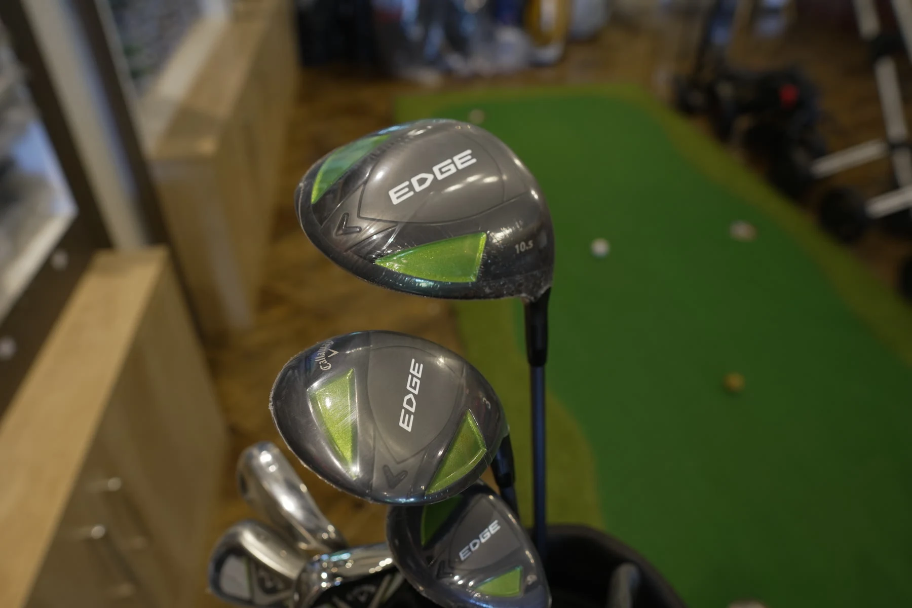 A Callaway Edge driver head resting in a golf bag beside the putting green
