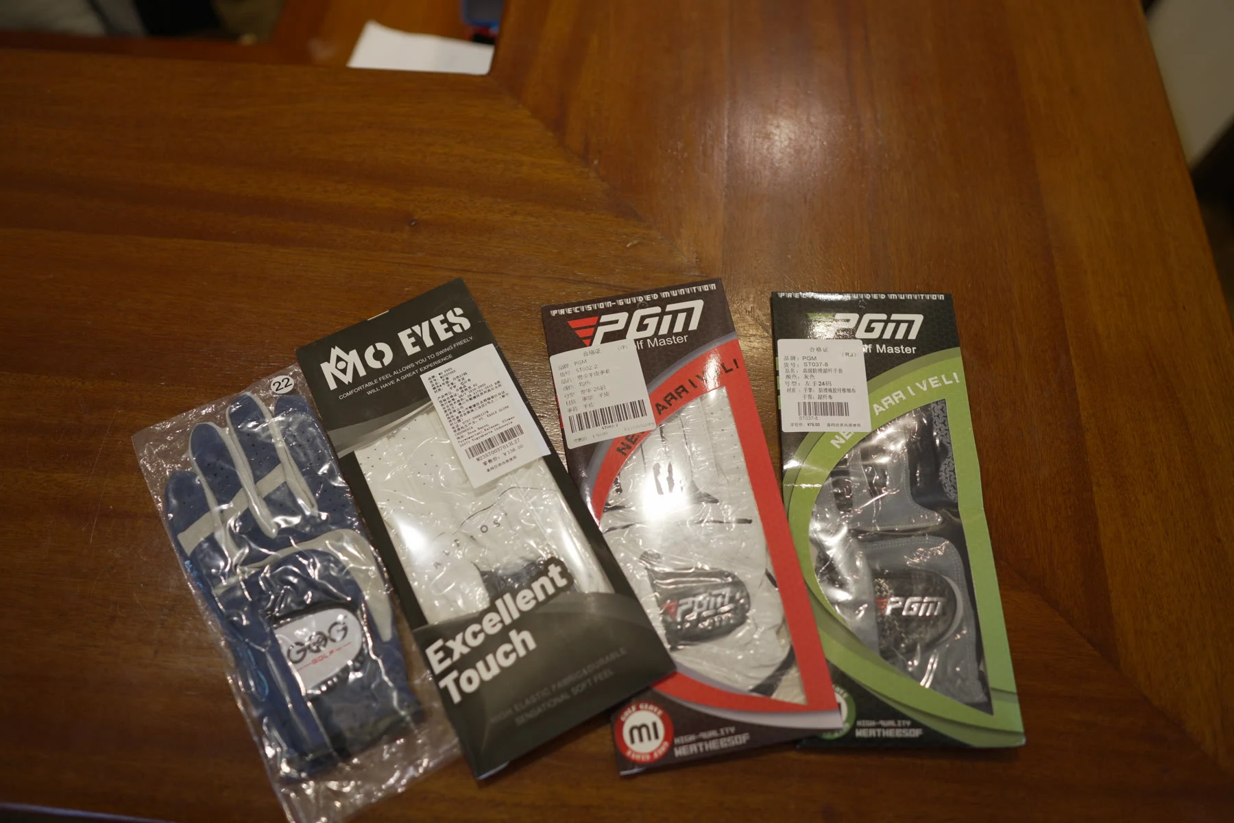 Packaged golf gloves in several brands displayed on a shop shelf
