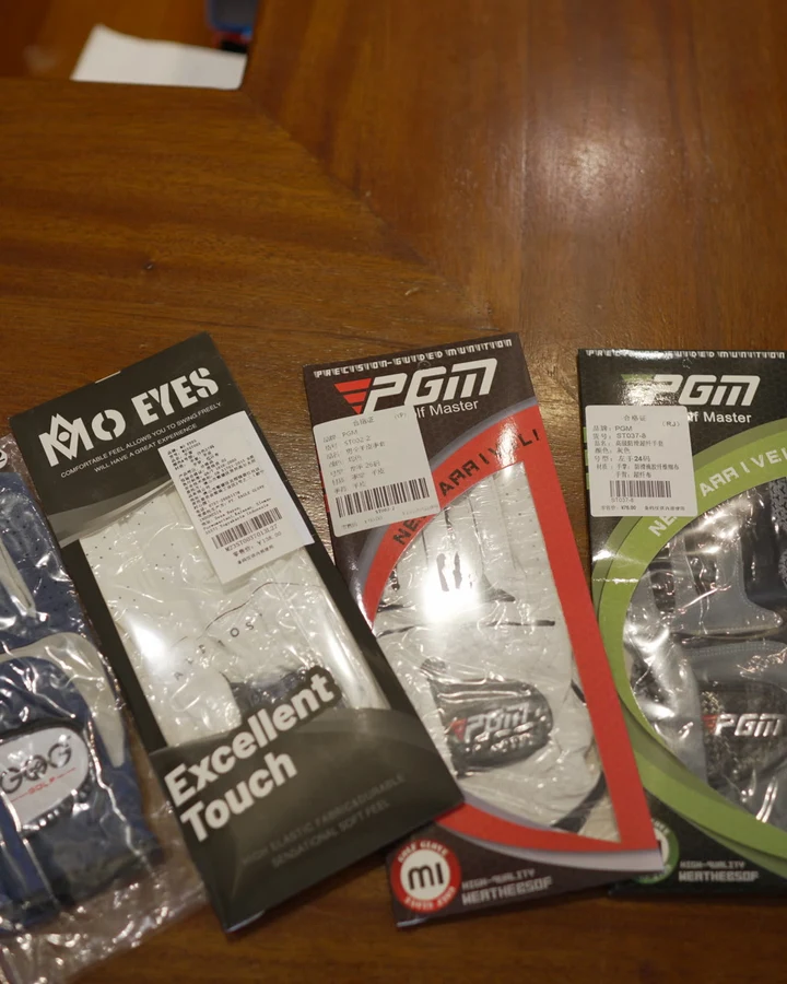 Packaged golf gloves in several brands displayed on a shop shelf