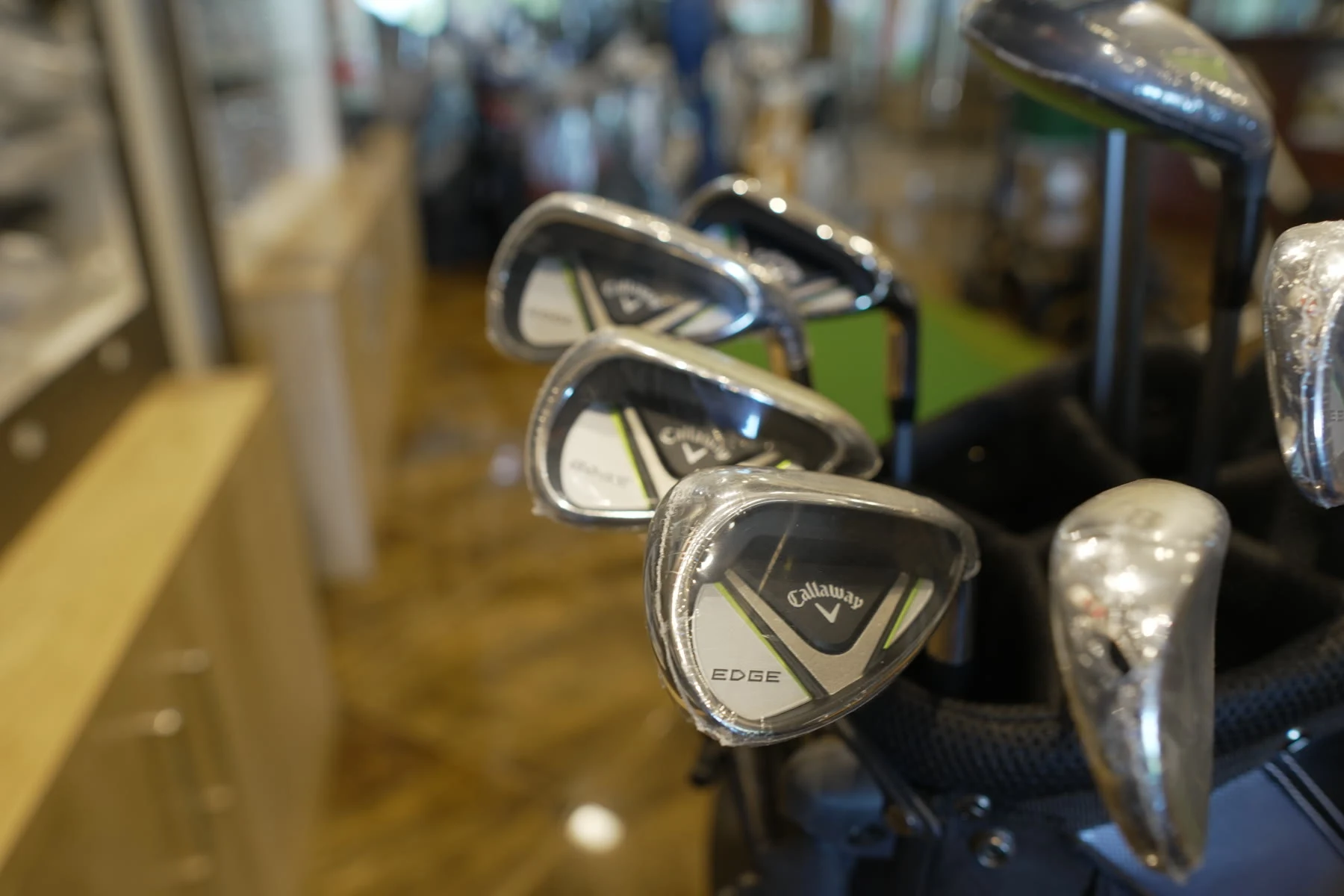 A set of Callaway Edge irons standing in a black golf bag inside the pro shop