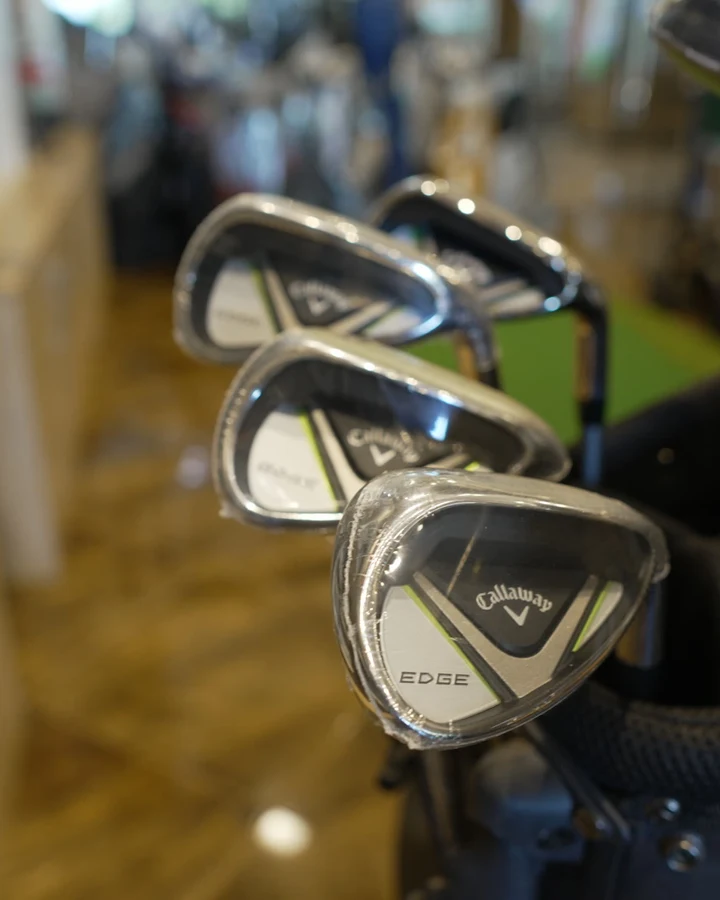 Callaway Edge irons standing in a black golf bag with the shop's shelving behind