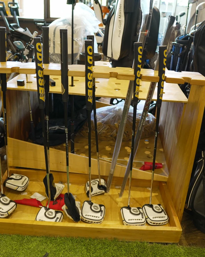 A wooden rack of blade and mallet putters standing on the shop floor