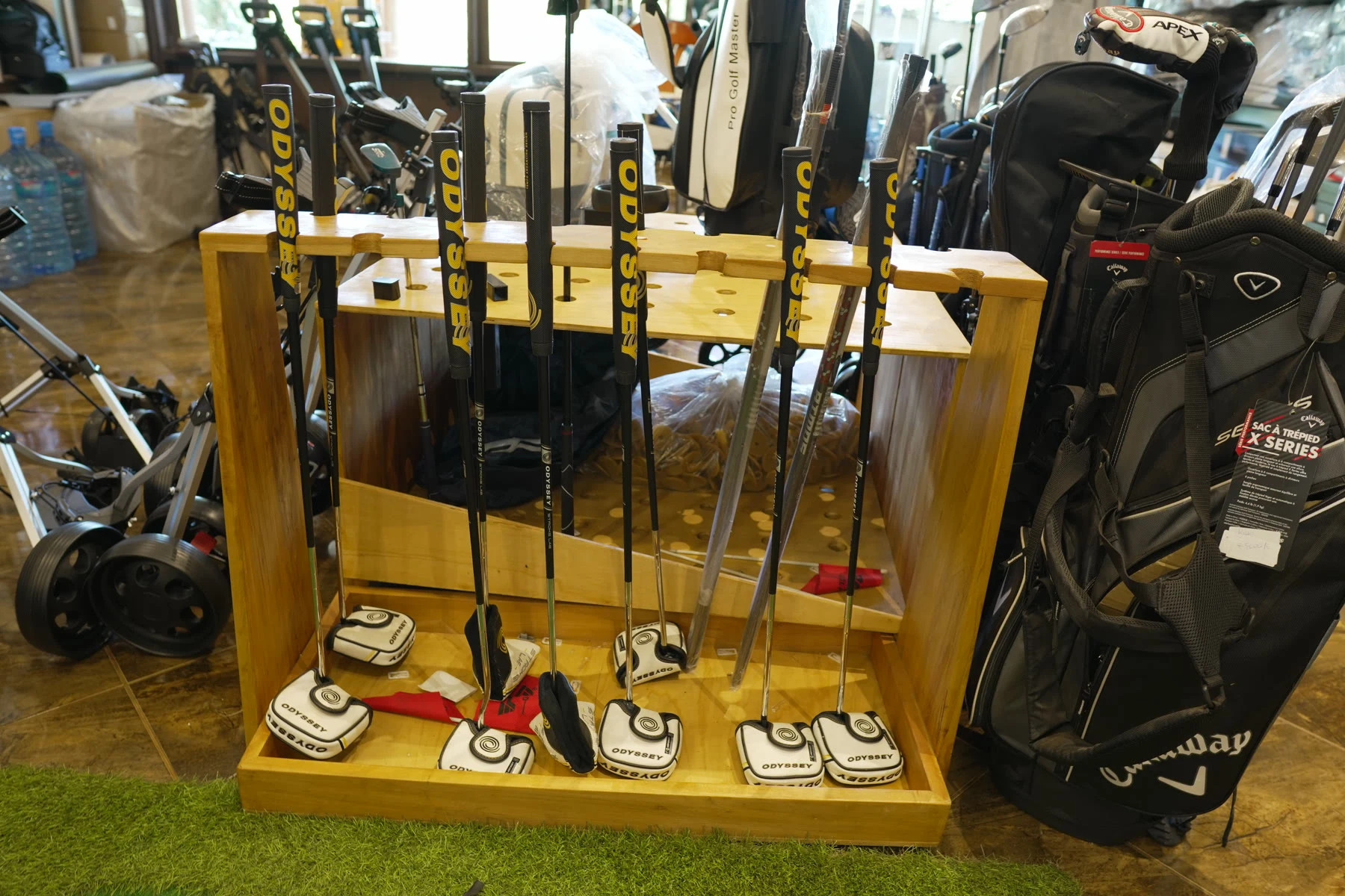 A wooden rack of blade and mallet putters standing on the shop floor