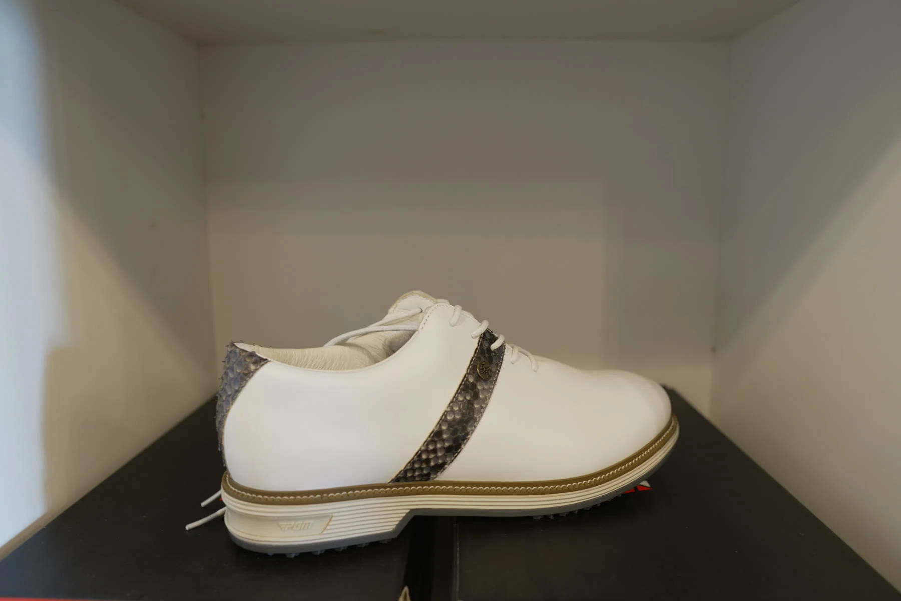 Two women's golf shoes in white and cream displayed on red shoe boxes