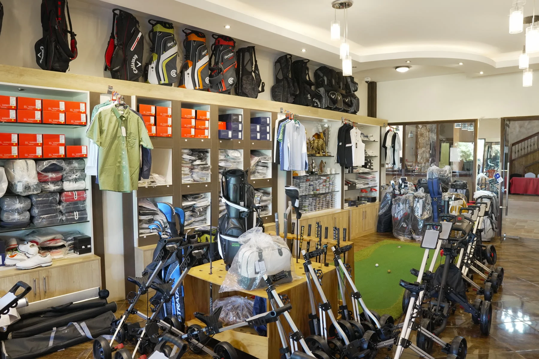 The interior of the pro shop, with bags and trolleys lined up along the green putting strip