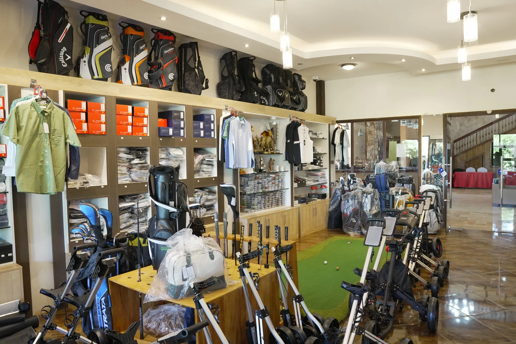 Inside the pro shop, looking down the aisle of bags and trolleys toward the counter