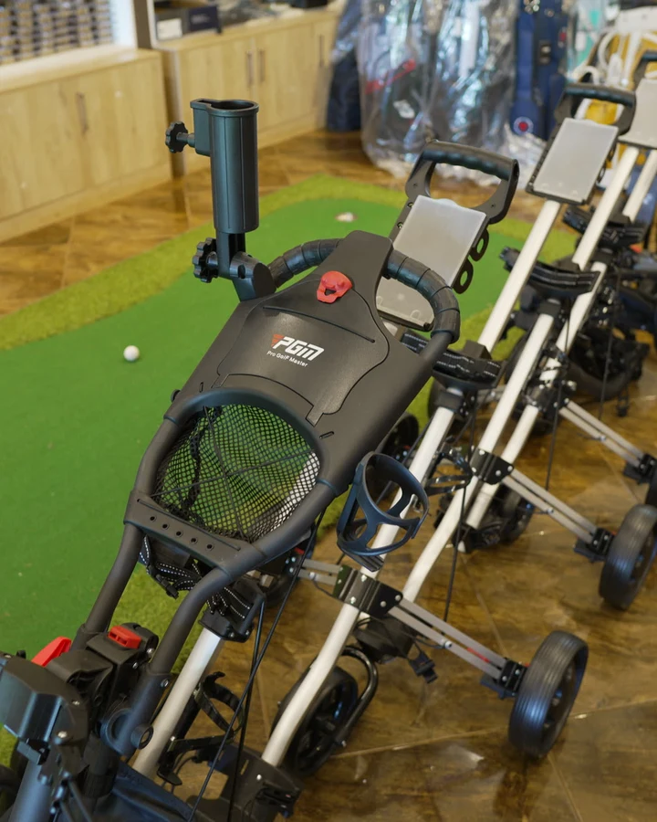 Folded and upright PGM push trolleys lined up on the shop's putting turf